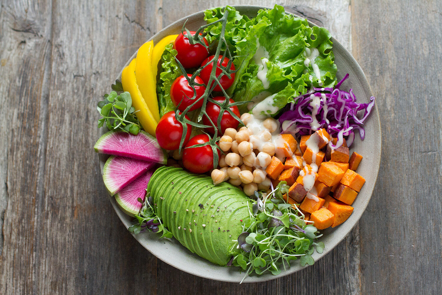 Schale mit Avocado, Kichererbsen, Süßkartoffel, Tomaten und Blattsalat